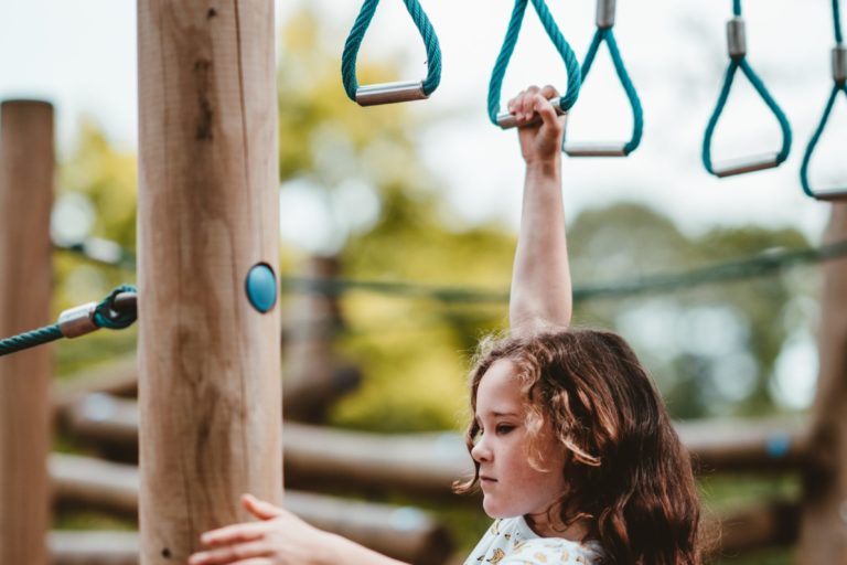child doing heavy work on monkey bars